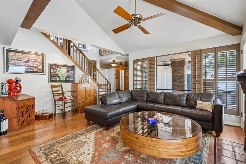 A living room features a vaulted ceiling with exposed beams, a sectional sofa, and stairs — 1256 MELISSA COURT, WINTER PARK, FL