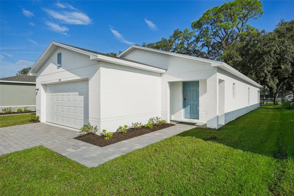 A white, single-story house with a blue front door, a garage, and a paved walkway — 2044 GOLDEN BEAK DRIVE, EAGLE LAKE, FL