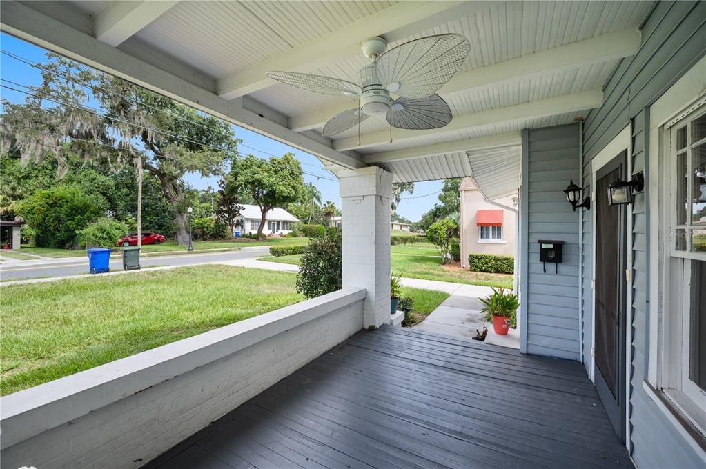A covered front porch with a ceiling fan, painted wood flooring, and a brick wall — 816 S INGRAHAM AVENUE, LAKELAND, FL