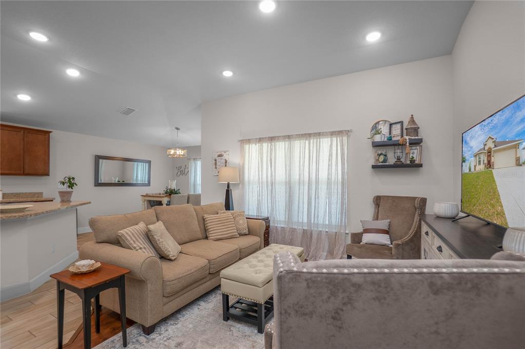 A living room features a beige sofa, a tufted ottoman, and a television on a console — 3271 N BURROUGHS PATH, BEVERLY HILLS, FL