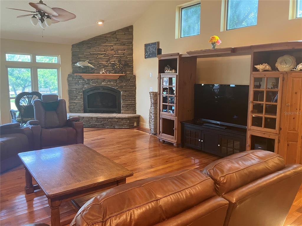 A living room features a stone fireplace, wood floors, and a large wooden entertainment center — 5361 CIRCLE DRIVE, WEEKI WACHEE, FL