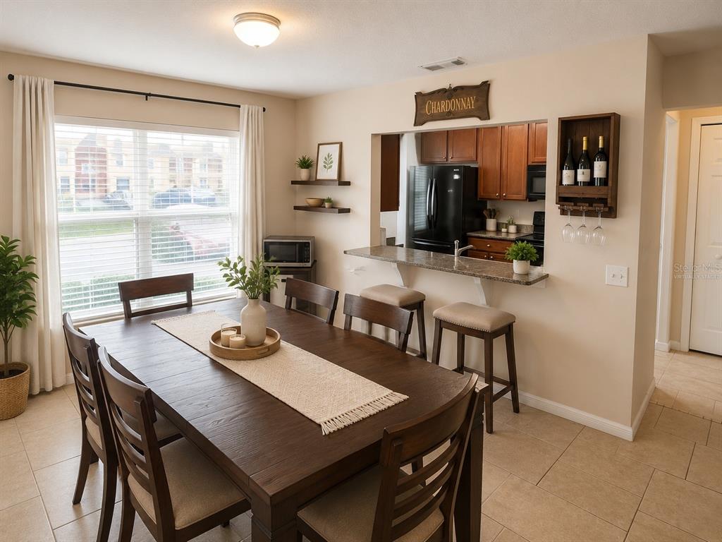 A dining area features a dark wood table with chairs, tile flooring, and a breakfast bar — 3858 ISLAND WAY, ST PETERSBURG, FL