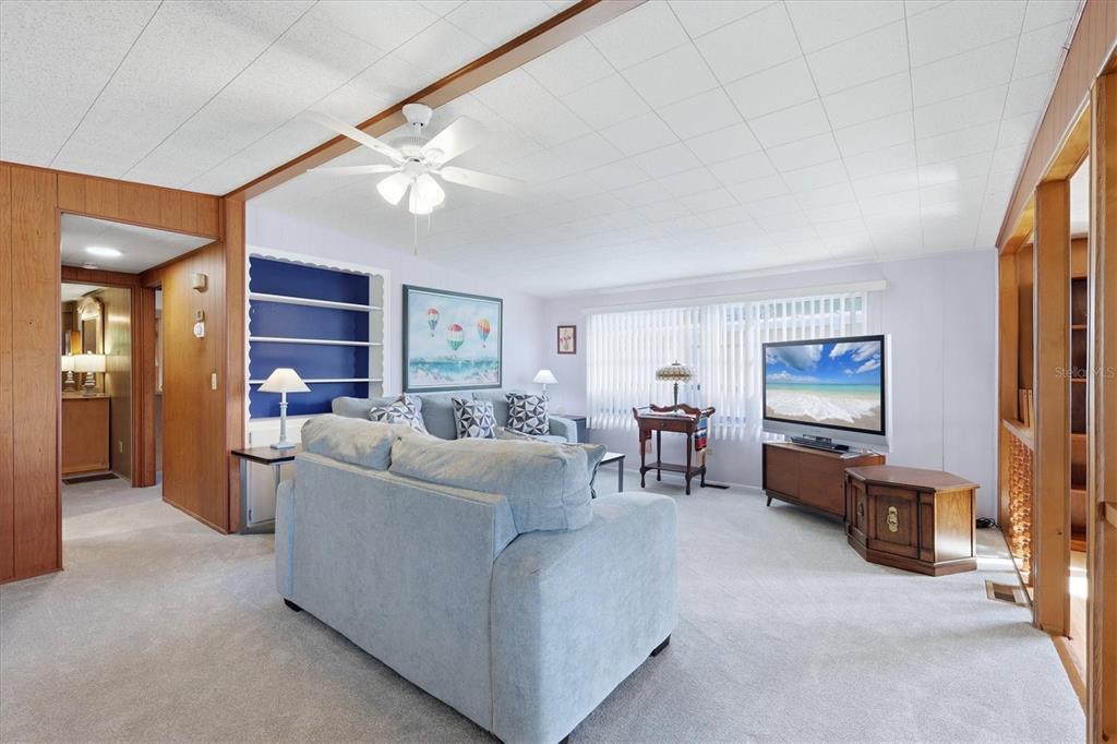 A living room features a light blue sofa, wood paneling, a ceiling fan, and carpeting — 1419 41ST AVENUE E, ELLENTON, FL
