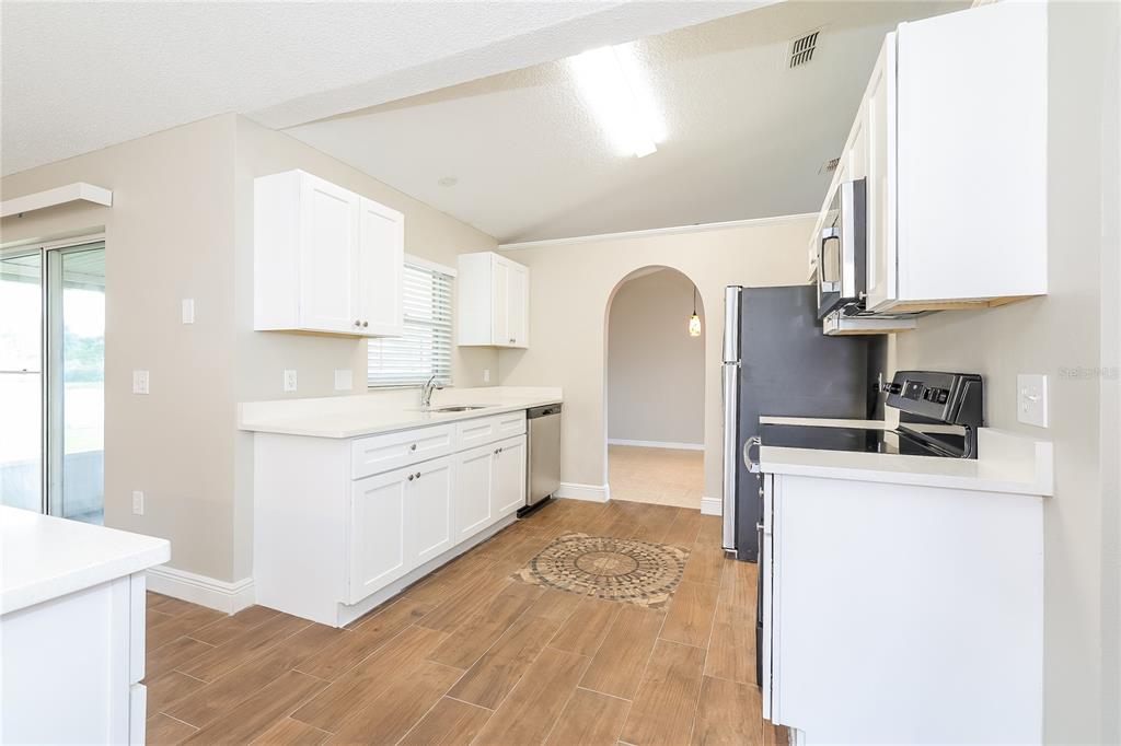 A kitchen with white cabinets, stainless steel appliances, and wood-look tile flooring — 817 ALBI COURT, KISSIMMEE, FL