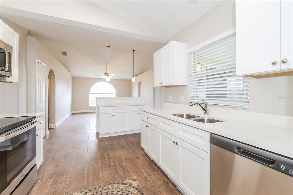 A kitchen with white cabinets, stainless steel appliances, and wood-look tile flooring — 817 ALBI COURT, KISSIMMEE, FL