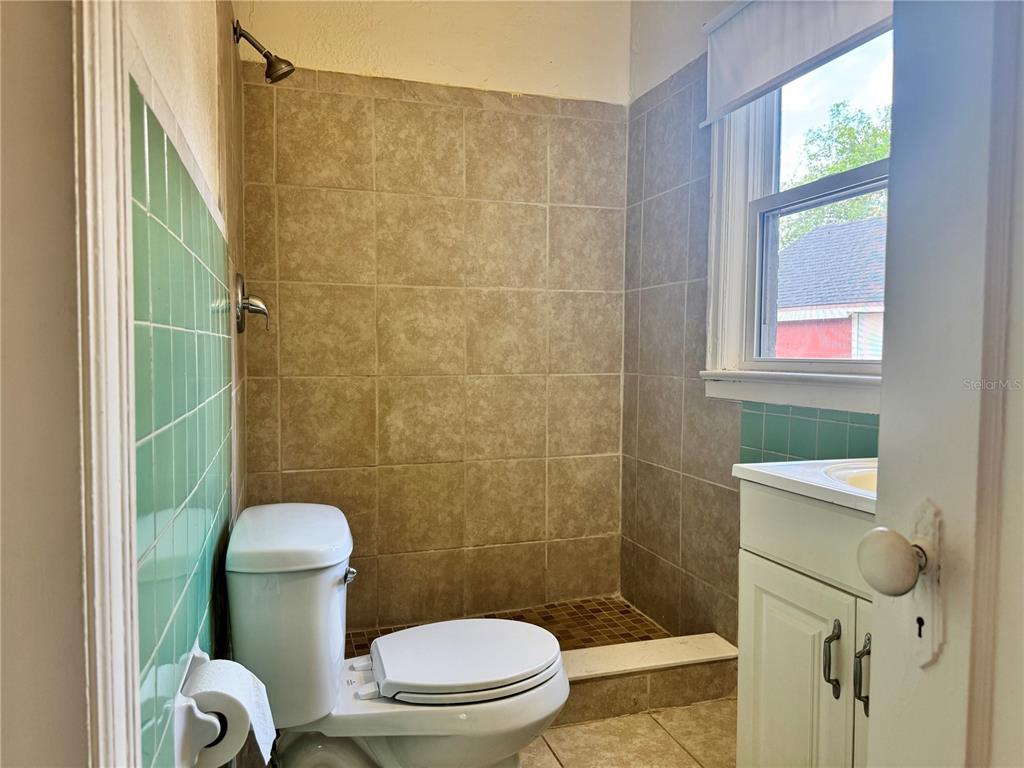 A bathroom features a walk-in shower with tan tiles, a toilet, and a vanity cabinet — 425 E SESSOMS AVENUE, LAKE WALES, FL
