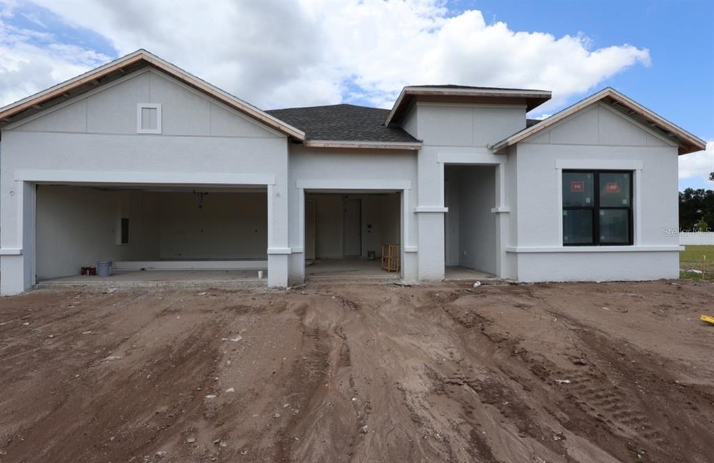 A newly constructed single-story house with a two-car garage and unfinished dirt front yard — 6811 HERON MEADOW DRIVE, SARASOTA, FL