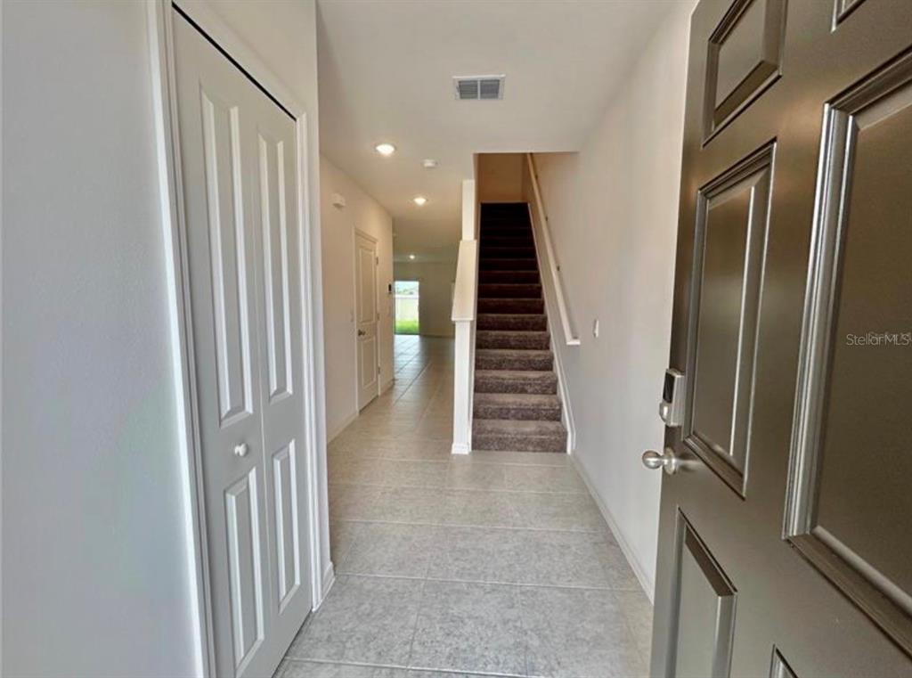 An entryway with tile flooring, a carpeted staircase, and a closed door on the left — 10759 IRONWOOD TREE WAY, SAN ANTONIO, FL