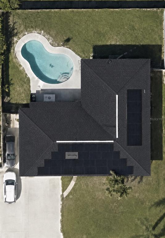 An aerial view shows a house with solar panels on the roof, a pool, and driveway — 440 CASSIA BLVD, SATELLITE BEACH, FL