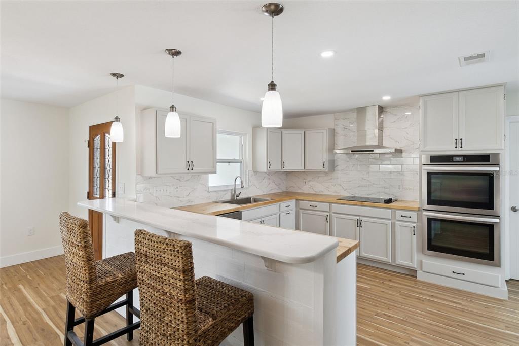 A kitchen with light gray cabinets, wood countertops, a breakfast bar, and stainless steel appliances — 440 CASSIA BLVD, SATELLITE BEACH, FL
