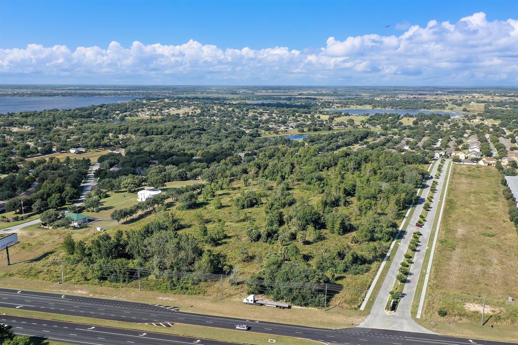 An aerial view shows a large, undeveloped wooded lot adjacent to a highway and road — 17545 US HWY 27, MINNEOLA, FL