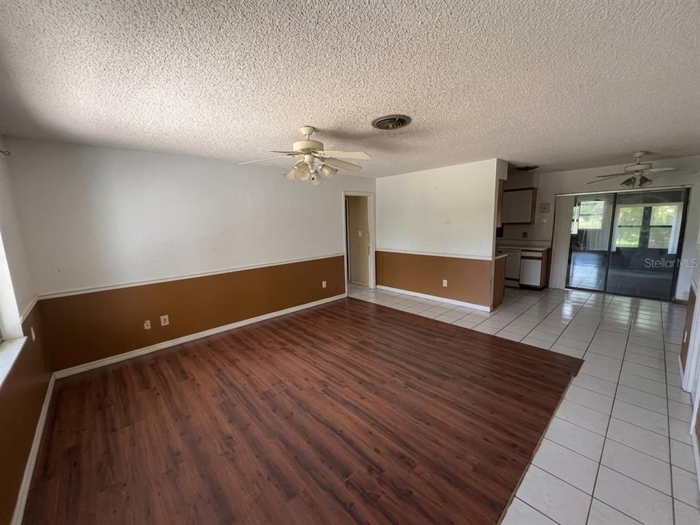 A living room with wood-look flooring, brown wainscoting, a ceiling fan, and an adjacent kitchen — 996 GRAYSON DRIVE, ORLANDO, FL