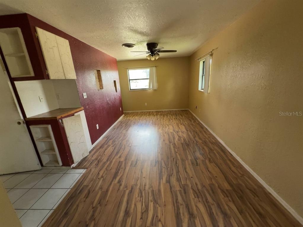 A room with wood-look flooring, a red accent wall, and a ceiling fan — 996 GRAYSON DRIVE, ORLANDO, FL