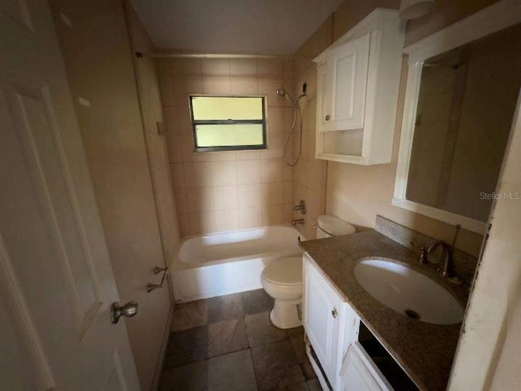 A bathroom with a tiled tub-shower combination, a white vanity, and a toilet — 996 GRAYSON DRIVE, ORLANDO, FL