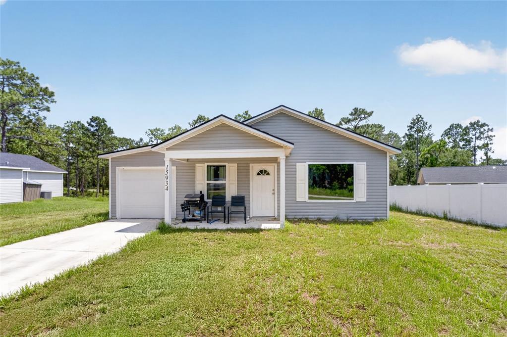 A single-story gray house with a front porch, garage, and white vinyl fence — 15934 SW 41ST STREET ROAD, OCALA, FL