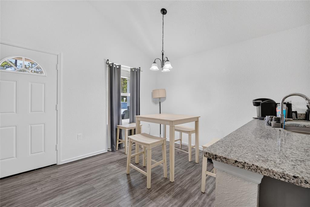 A dining area features a light wood table with stools, grey curtains, and granite countertops — 15934 SW 41ST STREET ROAD, OCALA, FL