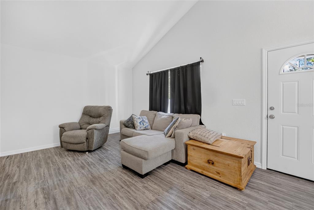 A living room features a gray sectional sofa, a recliner, a wooden chest, and vaulted ceilings — 15934 SW 41ST STREET ROAD, OCALA, FL