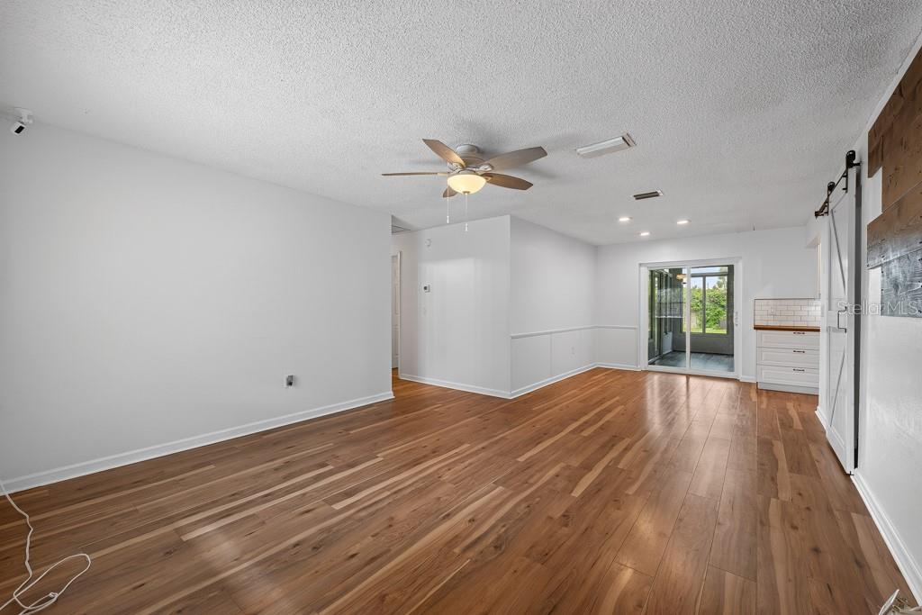 A living room features wood-look flooring, a gray sofa, a fireplace, and a dining area — 6070 73RD STREET N, ST PETERSBURG, FL