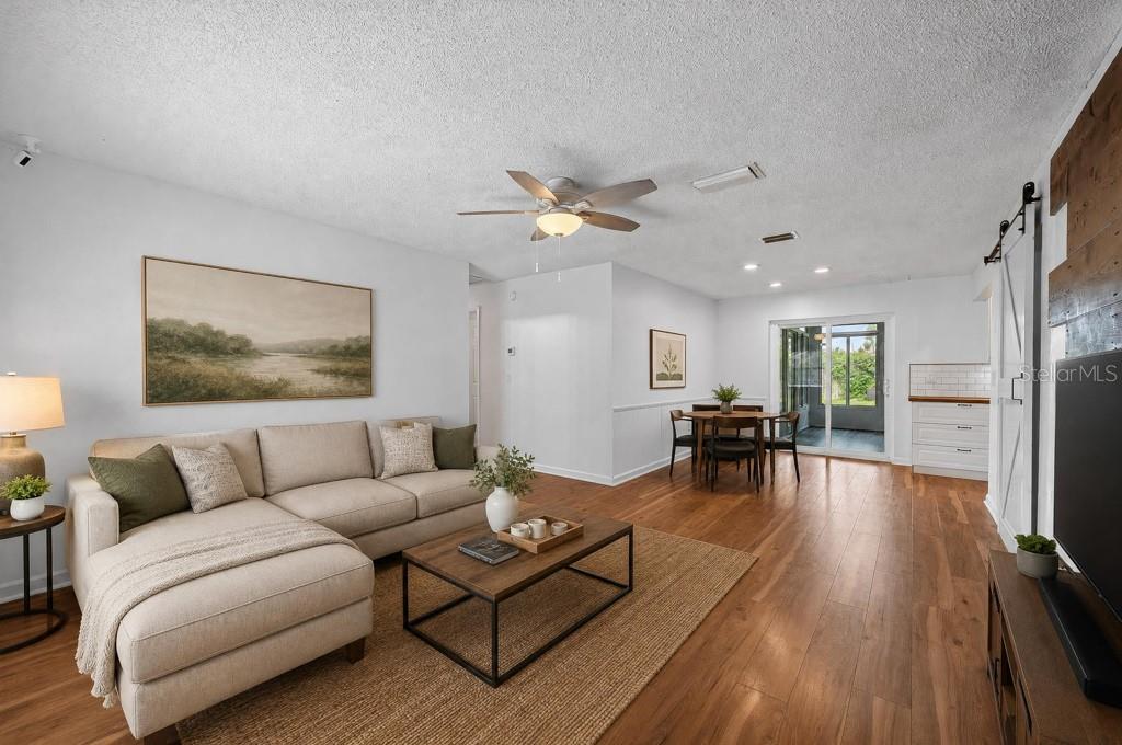 A living room with wood flooring, a ceiling fan, a barn door, and a dining area — 6070 73RD STREET N, ST PETERSBURG, FL