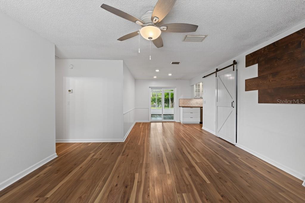 A living room features gray reclining sofas, wood flooring, and a ceiling fan — 6070 73RD STREET N, ST PETERSBURG, FL