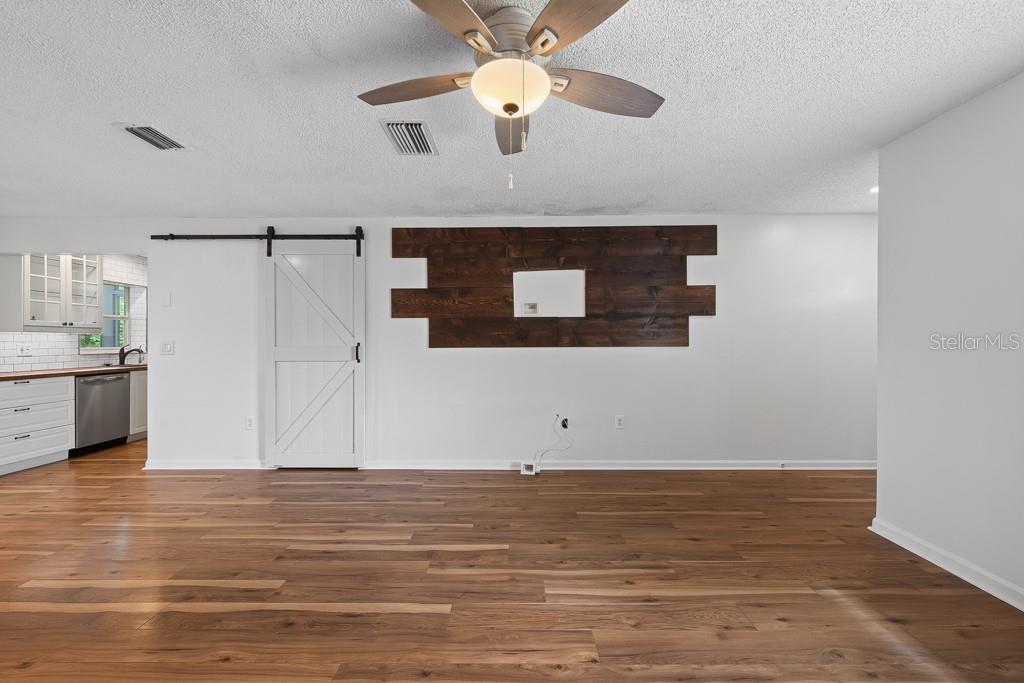 A living room features wood-look flooring, a fireplace, a television, and two gray sofas — 6070 73RD STREET N, ST PETERSBURG, FL