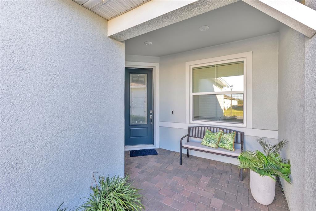 A covered entryway features a dark blue front door, a bench, and a potted plant — 2434 N CLIFF WAY, ST CLOUD, FL