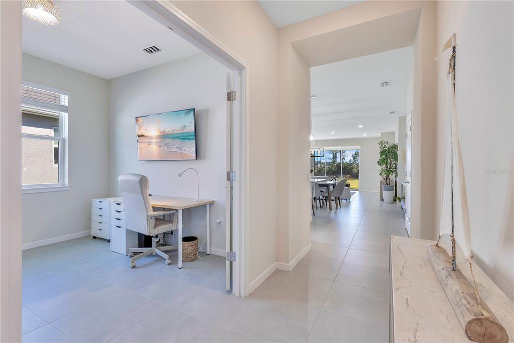 A home office with a desk and chair sits beside a hallway leading to a dining area — 2434 N CLIFF WAY, ST CLOUD, FL