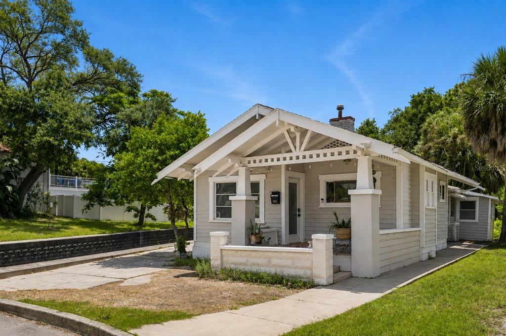 A light-colored bungalow with a front porch and a concrete driveway under a blue sky — 558 10TH AVE S, ST PETERSBURG, FL