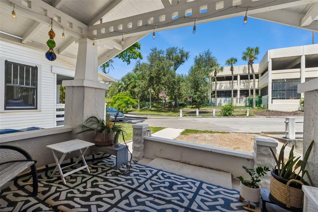 A covered front porch with a patterned rug, potted plants, and string lights — 558 10TH AVE S, ST PETERSBURG, FL