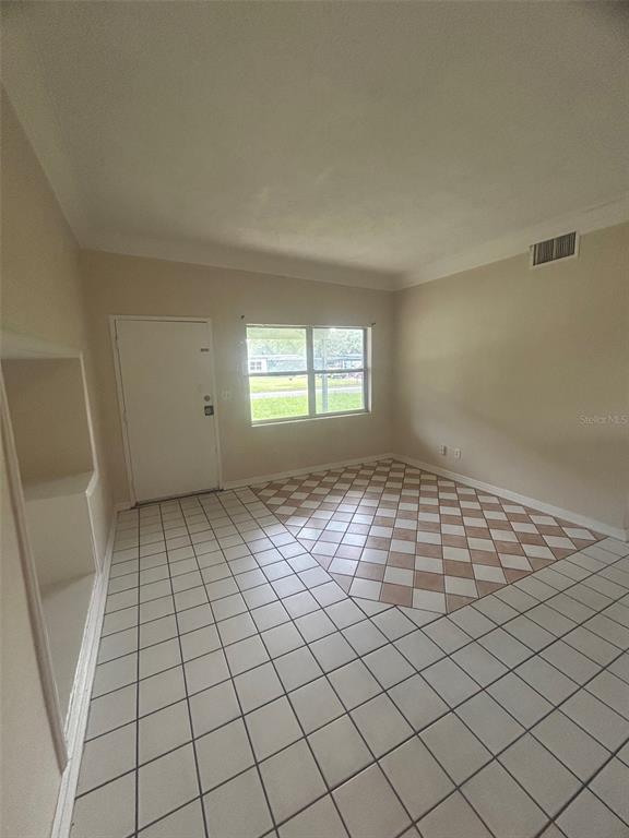 An interior room with white walls, a white door, and light-colored tiled flooring — 127 COUNTRY CLUB DRIVE, SANFORD, FL