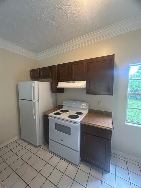 A kitchen features dark wood cabinets, a white refrigerator, a white stove, and tiled flooring — 127 COUNTRY CLUB DRIVE, SANFORD, FL