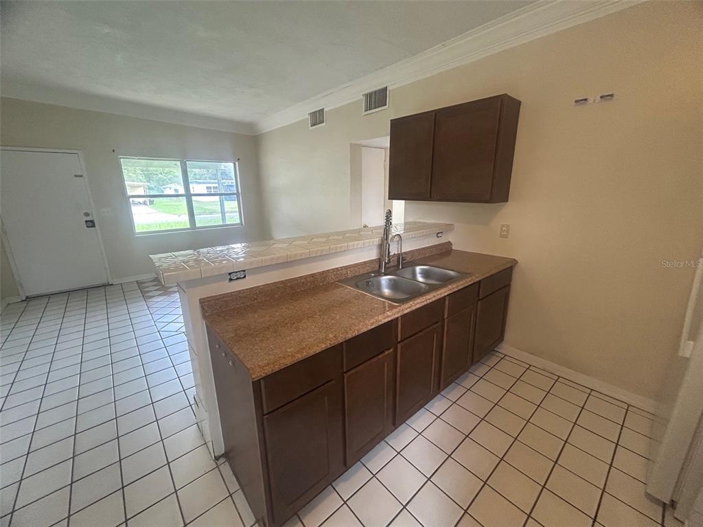 A kitchen with dark wood cabinets, granite countertops, and white tile flooring — 127 COUNTRY CLUB DRIVE, SANFORD, FL