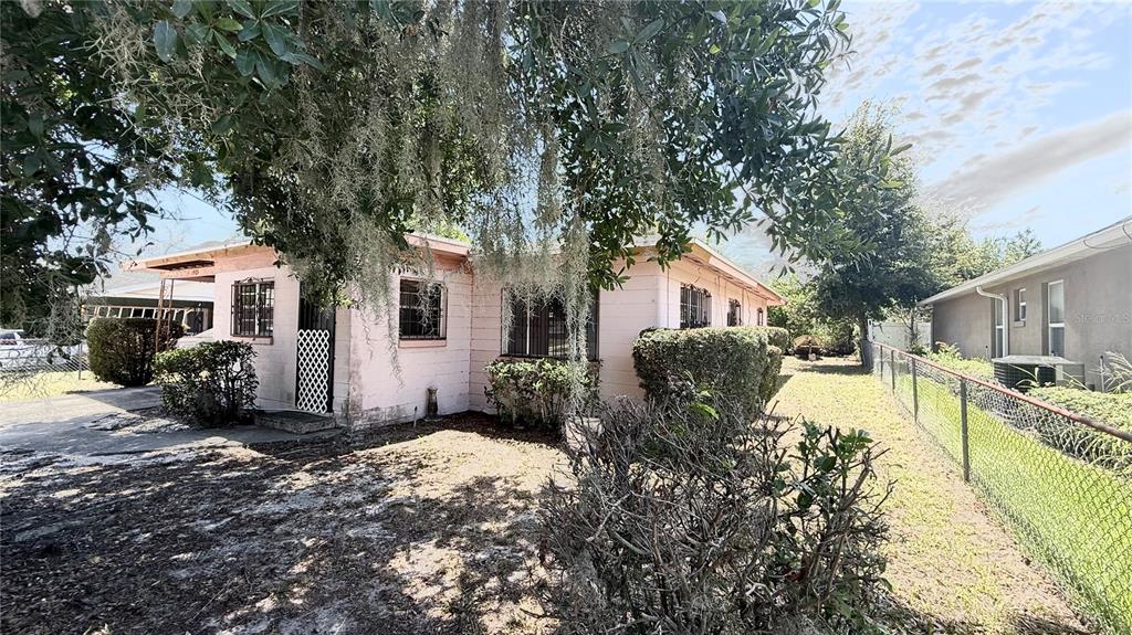 A pink, single-story house with a chain-link fence and Spanish moss hanging from trees — 1903 3RD STREET NE, WINTER HAVEN, FL