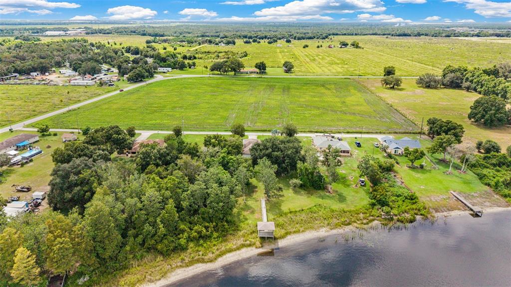 An aerial view shows a waterfront property with a dock, trees, and nearby houses — 930 ALBRITTON WAY, LAKE WALES, FL