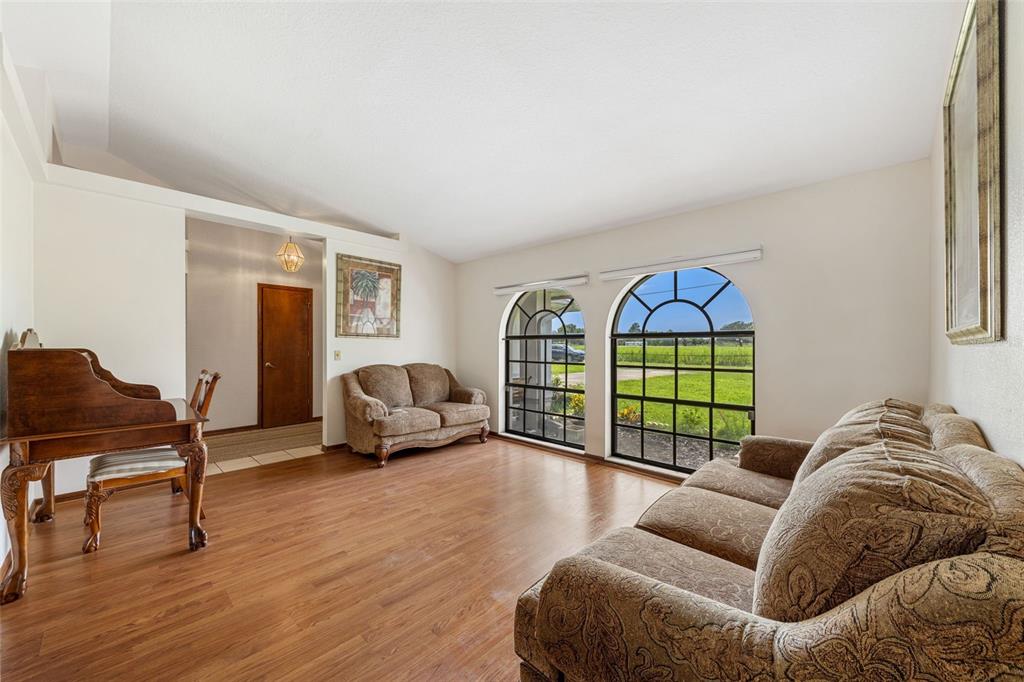 A living room with wood flooring, two arched windows, and two patterned brown sofas — 930 ALBRITTON WAY, LAKE WALES, FL