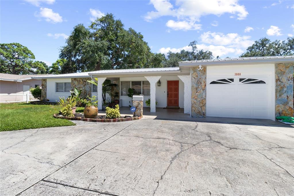 A single-story house with a white garage, stone accents, and a red front door — 3000 PONCE DE LEON WAY S, ST PETERSBURG, FL