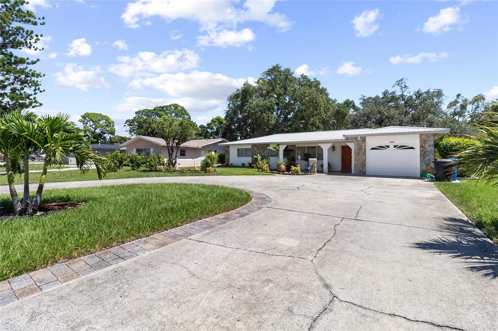 A single-story house with a white garage and a large concrete driveway under a sky — 3000 PONCE DE LEON WAY S, ST PETERSBURG, FL