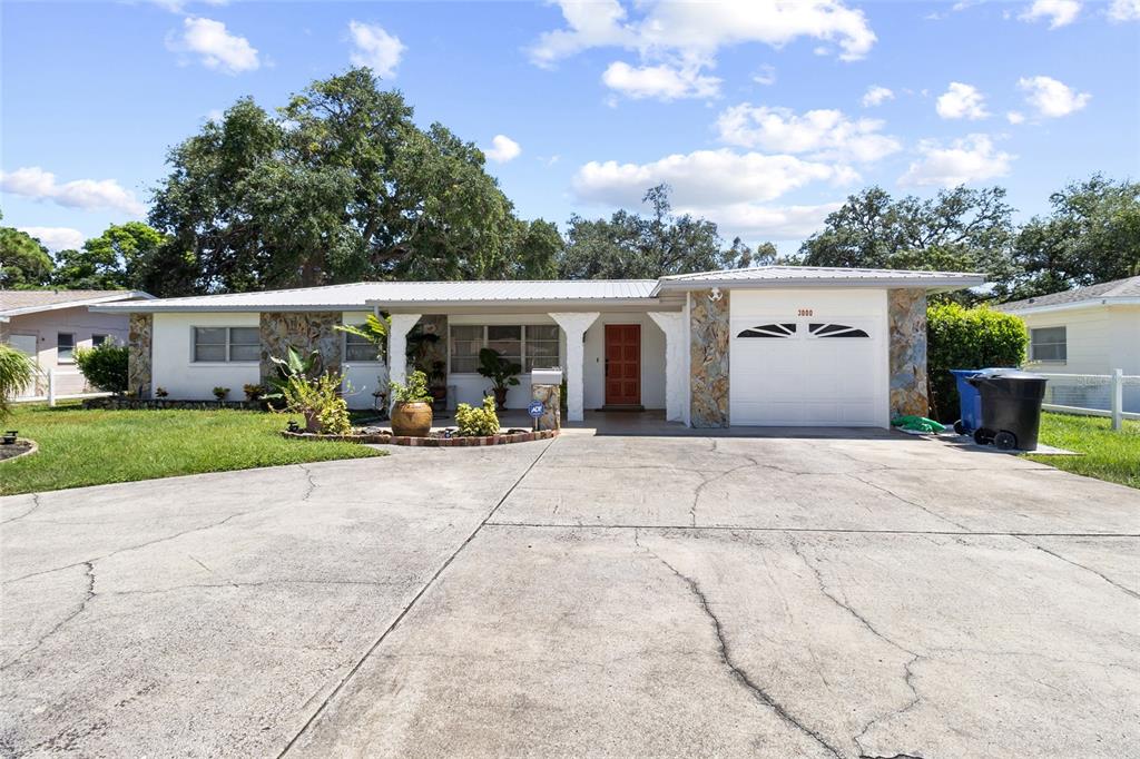 A single-story house features a stone facade, a white garage, and a concrete driveway — 3000 PONCE DE LEON WAY S, ST PETERSBURG, FL