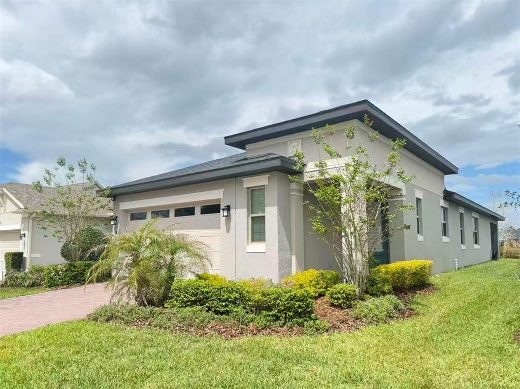 A single-story house with a beige stucco exterior, a garage, and a landscaped front yard — 3434 SAGEBRUSH STREET, HARMONY, FL