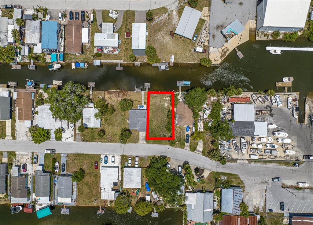 This aerial view shows a vacant rectangular lot situated between two houses along a canal — 6845 SANDERLING LANE, HUDSON, FL