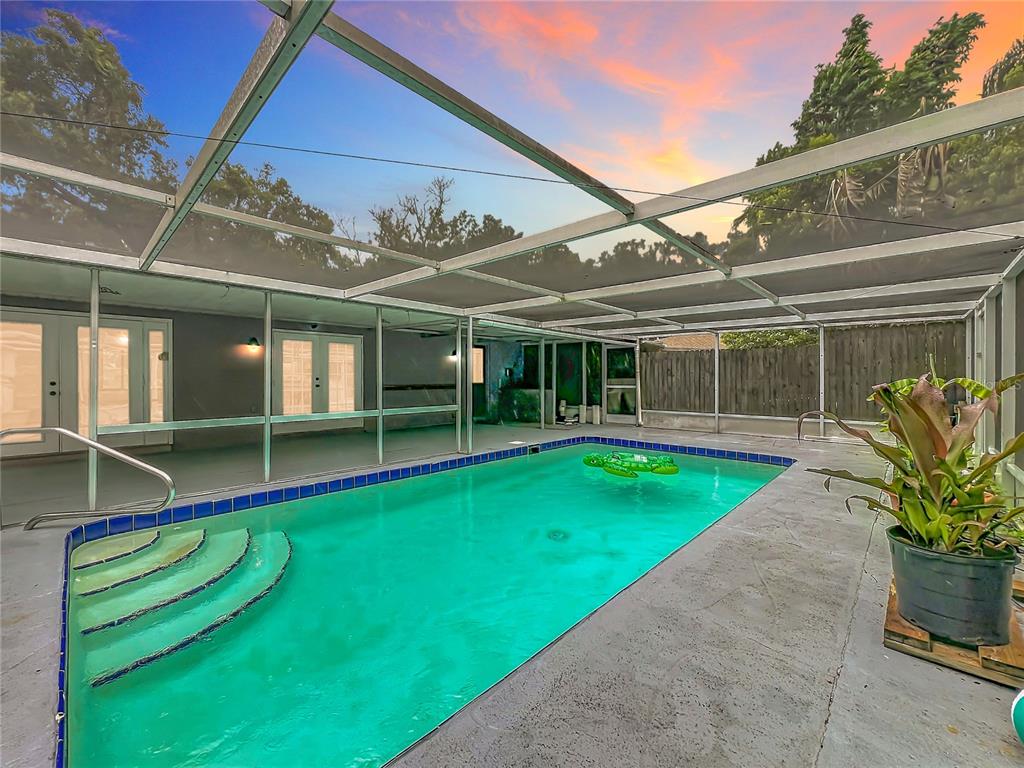 A screened-in swimming pool with steps and a patio area under a sunset sky — 300 PINECREST ROAD, MOUNT DORA, FL