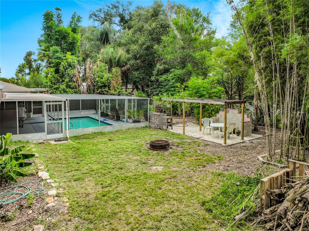 A backyard features a screened-in swimming pool, a covered patio area, and a fire pit — 300 PINECREST ROAD, MOUNT DORA, FL