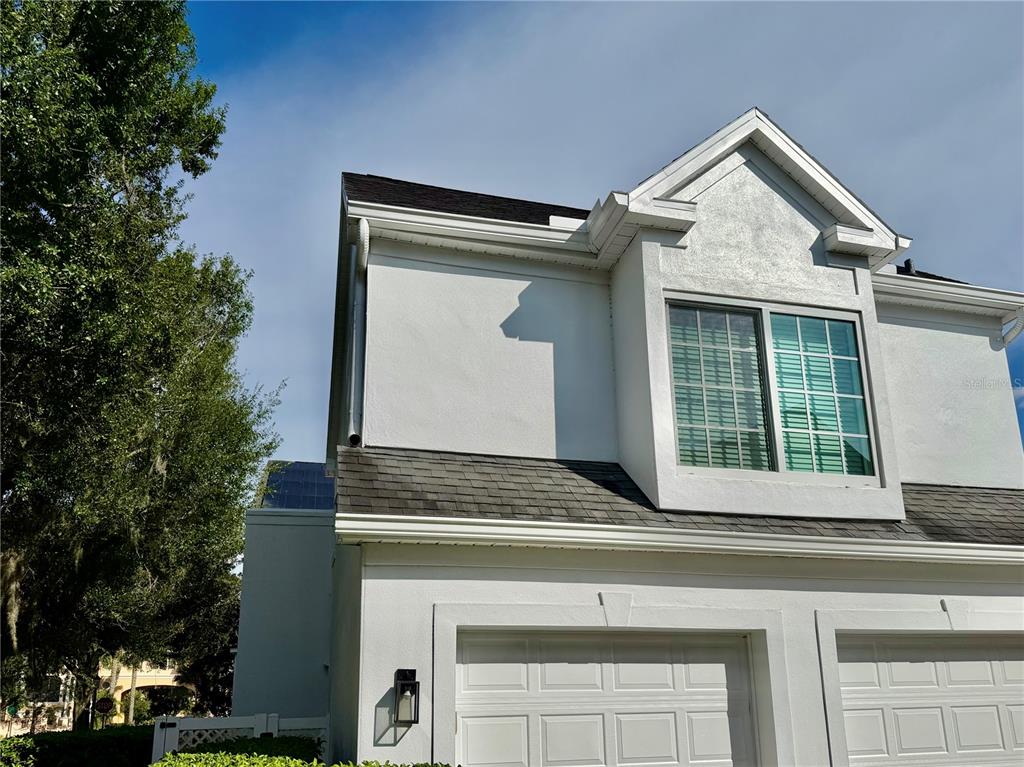 Exterior view of a two-story home with a white stucco facade and a garage — 415 CELEBRATION AVENUE UNIT B, CELEBRATION, FL