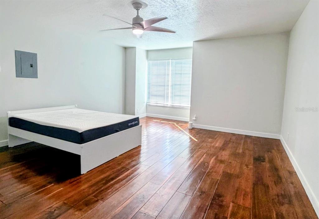 A bedroom with hardwood floors, a white bed frame, a ceiling fan, and a window — 415 CELEBRATION AVENUE UNIT B, CELEBRATION, FL