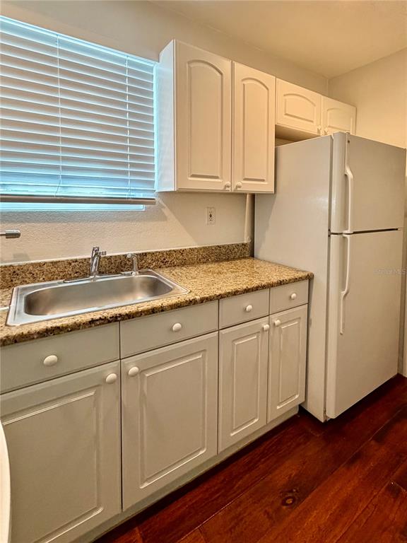 A kitchen features white cabinets, granite countertops, a stainless steel sink, and a white refrigerator — 415 CELEBRATION AVENUE UNIT B, CELEBRATION, FL