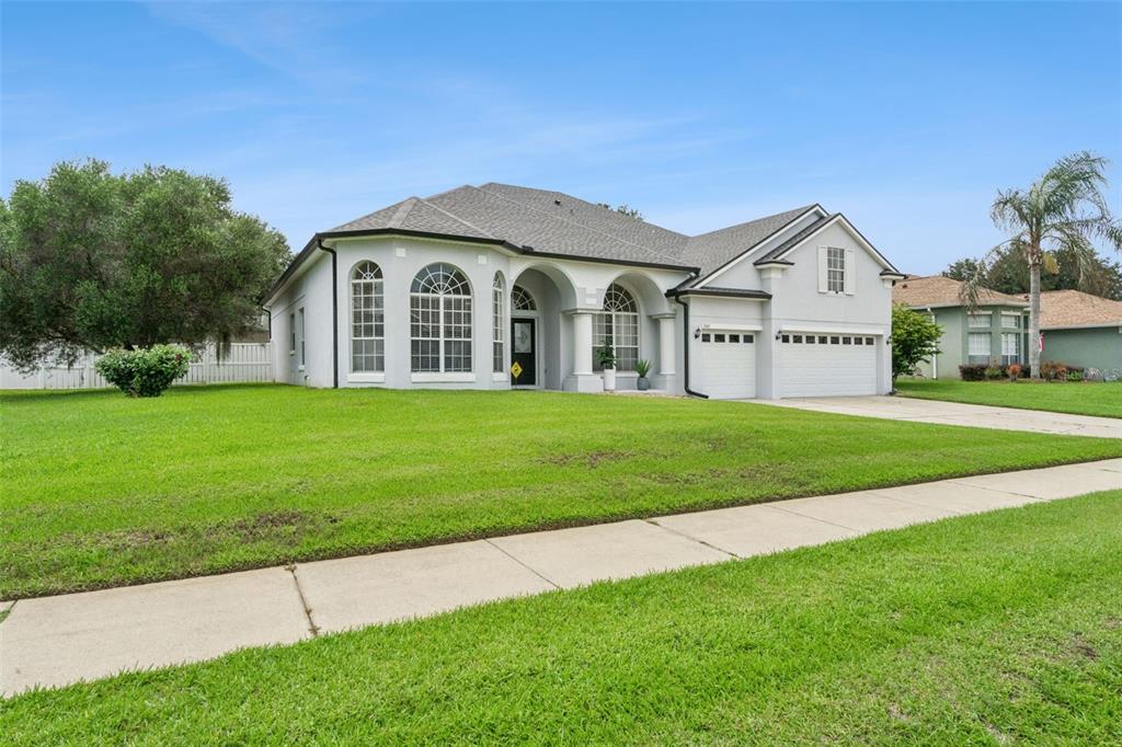 A single-story house with a light-colored stucco exterior, arched windows, and a two-car garage — 13163 LAKESHORE GROVE DRIVE, WINTER GARDEN, FL