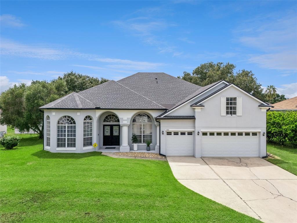 A single-story house with a gray roof, white stucco exterior, and a three-car garage — 13163 LAKESHORE GROVE DRIVE, WINTER GARDEN, FL
