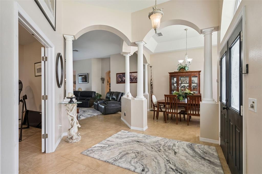 An entryway with tile floors, arched openings, white columns, and a view into the dining room — 13163 LAKESHORE GROVE DRIVE, WINTER GARDEN, FL