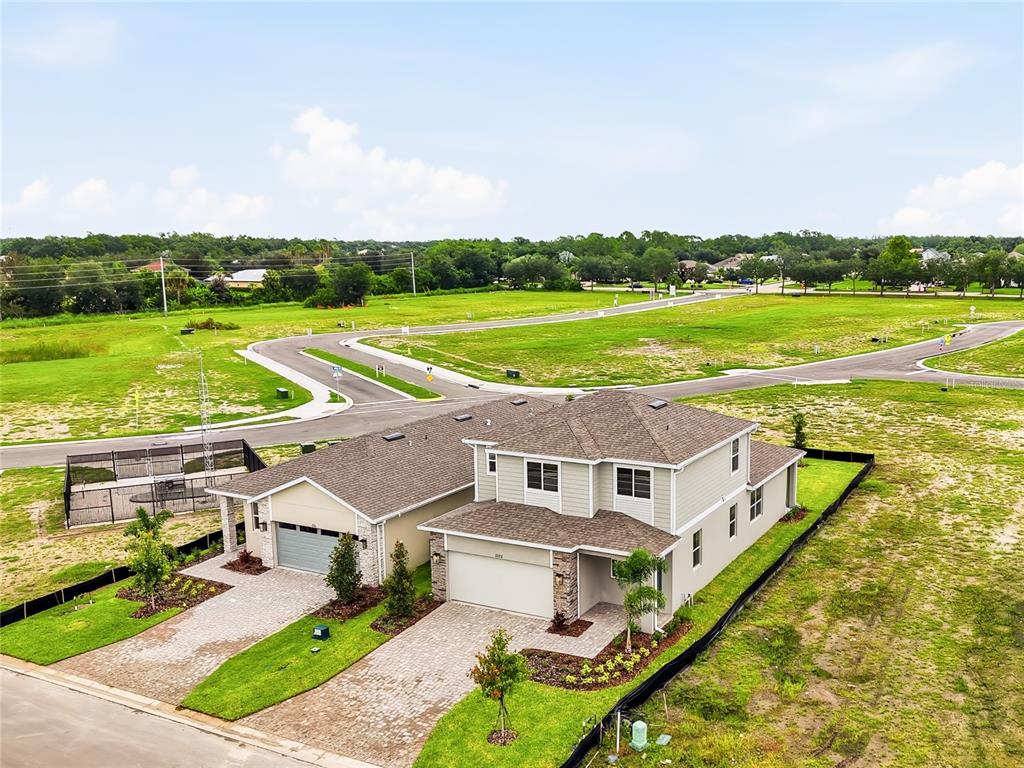 An aerial view shows three new houses under construction near a pond and paved road — 2322 ANDERS DRIVE, PARRISH, FL