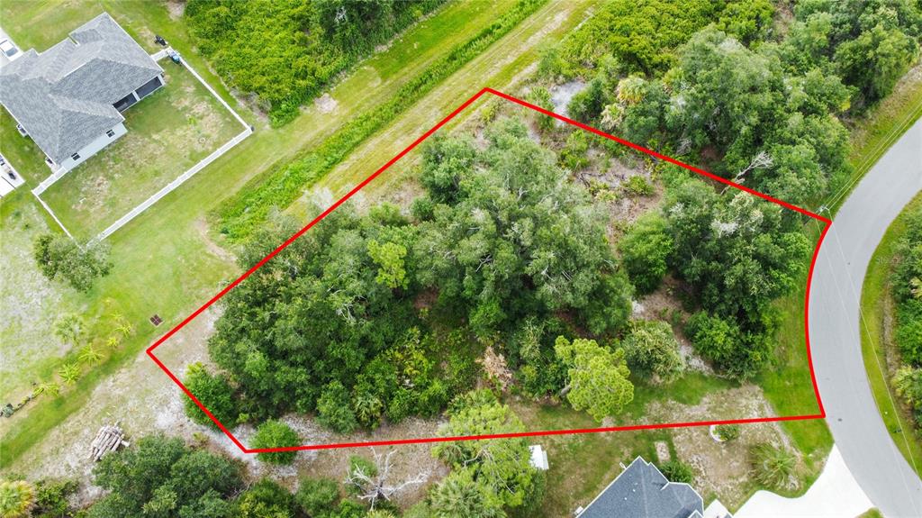 An aerial view shows a wooded, irregularly shaped vacant lot outlined in red — ANCIENT ROAD, NORTH PORT, FL